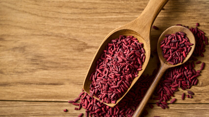 top view flat lay pile of ferment red yeast rice or Angkak in wood scoop on wooden table rustic food background with copy space