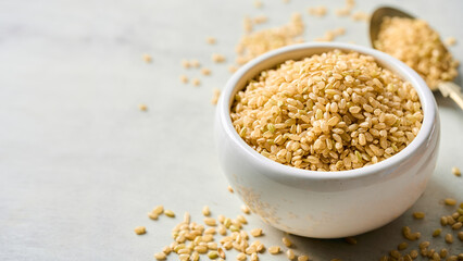 closeup dry brown short grain unpolished rice or Japanese brown rice in ceramic bowl on white table background with copy space