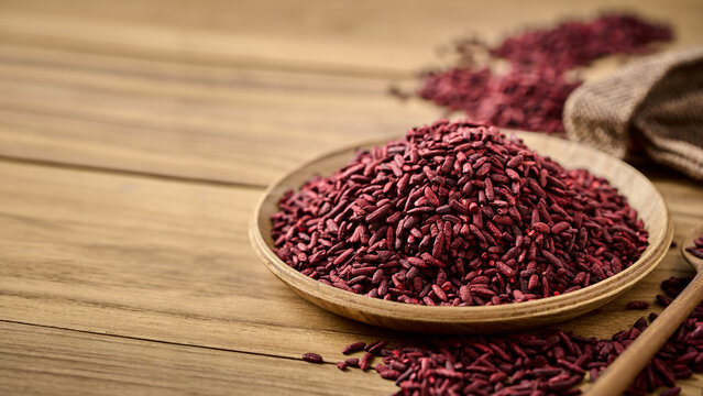 closeup pile of ferment red yeast rice or Angkak in wood bowl on wooden table rustic food background with copy space
