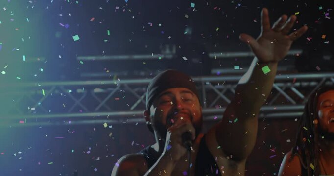 Bandmates performing on music stage, highlighting lead singer with floating confetti and lighting