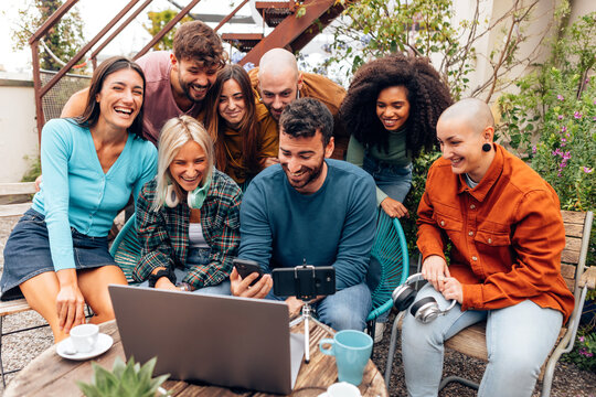 Content creators team laughing and working together on a video project using laptop and smartphone