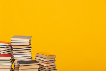 Stacks of old books for teaching in the library on a yellow background at school
