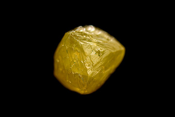 Closeup natural rough uncut fancy yellow diamond crystal on dark background (selective focus)