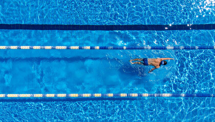 Male swimmer with a strong body swimming in a big swimmingpool indoors