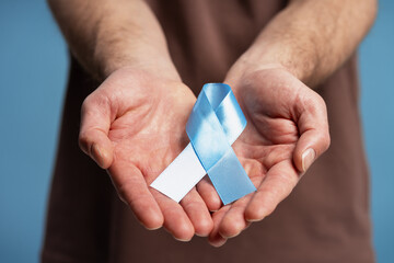 Man holding blue and white ribbon supporting prostate cancer awareness