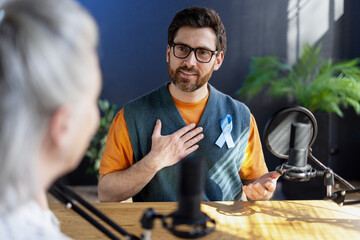 Radio host speaking about prostate cancer prevention wearing a light blue ribbon during a podcast interview