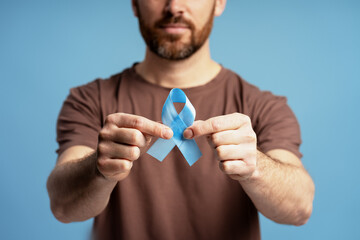 Man holding light blue ribbon for prostate cancer awareness