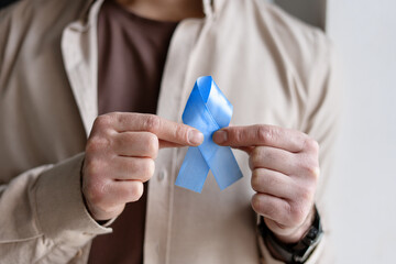 Man showing blue ribbon, colon cancer awareness and men's health symbol