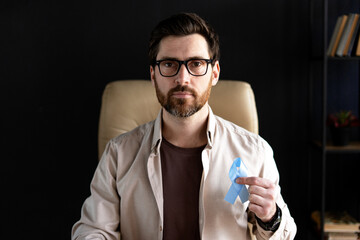Man showing blue ribbon for prostate cancer awareness month