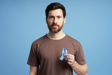 Man showing blue prostate cancer awareness ribbon on blue background