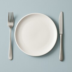 A top-down view of a minimalistic, modern dining setup featuring a sleek, white plate with subtle texture on a soft, pastel blue background.