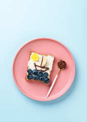 Sweet toast with blueberry and chocolate paste. Flat lay on blue.
