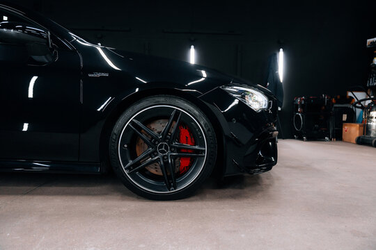 Close-up view of Mercedes-Benz CLA 45S AMG C118 front wheel with red brake caliper and AMG rim &ndash; luxury performance car showcased in detailing studio. Marketing materials, advert or press content.