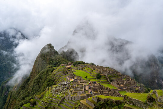 Panoramic view of Machu Picchu ruins surrounded by misty mountains, Peru