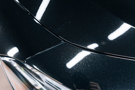 Close-up shot of metallic black Mercedes-Benz CLA 45 S AMG body lines under studio lighting &ndash; sharp design contours, premium finish, reflective surface and high gloss paint detail for luxury showcase