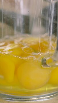 Vertical Video of Raw Eggs in Measuring Jug with One Egg Being Poured in Slow Motion. Ready to Mix to make Scrambled Eggs or Cake Mixture.