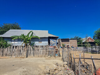 Charming fisherman’s house in a rural village, surrounded by a bamboo fence under the bright sun.