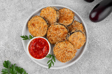 Baked garlic crispy eggplant with tomato sauce on a plate. Vegetarian food. Selective focus, top view.