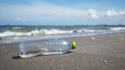 Obraz premium Used plastic water bottle in the sea washed ashore by waves. Plastic water waste pollution on the beach. Marine environmental issues.
