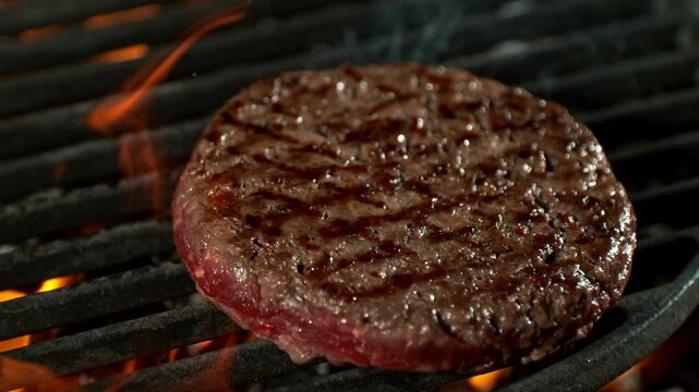 Super Slow Motion Shot of Flipping Hamburger Meat on Hot Grill with Flames and Embers at 1000fps.