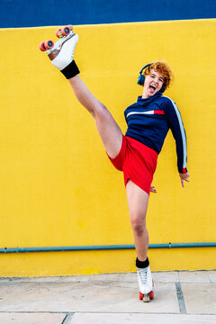 Woman roller skating energetically with headphones against a yellow background