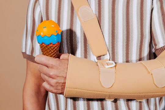 Man with tennis elbow wearing arm sling holding toy ice cream cone