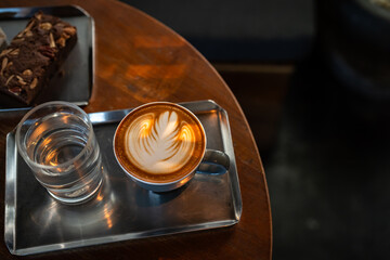 Hot coffee latte with latte art milk foam in cup mug and Homemade Brownie on wood desk on top view. As breakfast In a coffee shop at the cafe,during business work concept,vintage style
