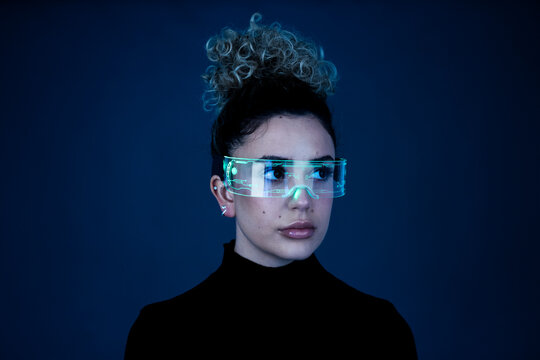 Woman with curly hair wearing AR glasses in a studio setting