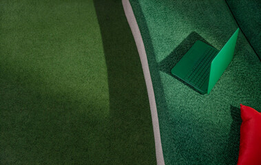 Green laptop on a sofa with red pillow and green carpet