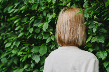 Woman standing against a green leaves wall promoting mental health and work-life balance