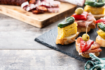 Traditional Spanish pintxos on wooden table. Copy space