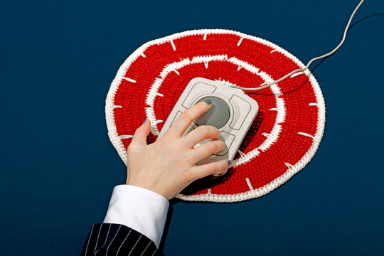 Hand using a vintage trackball mouse on a crochet target pattern