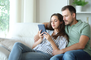 Obraz premium Couple reading together the same ebook at home