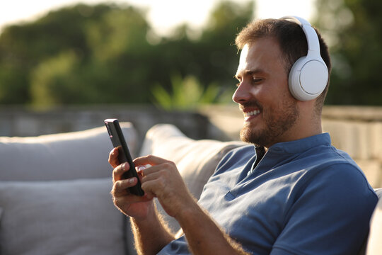 Happy man in a terrace listening audio using phone