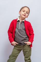 Young boy in red jacket and gray polo shirt with collar, hands in pockets, stands confidently on light backdrop. His khaki pants complete the casual attire and relaxed pose