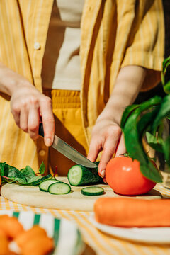 Naklejki Woman preparing a healthy summer salad indoors by cutting vegetables