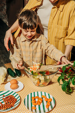 Mother and son preparing a summer salad together indoors
