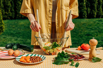 Woman preparing a summer salad with fresh vegetables outdoors