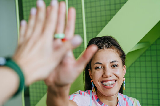 Young woman smiling and giving a high five indoors
