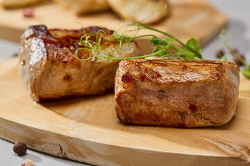 Grilled pork tenderloin on wooden board, natural light, warm color tones, minimal composition