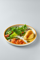 Minimalist Plate of Fried Cheese with Fresh Vegetable Salsa and Greens on Soft Gray Background