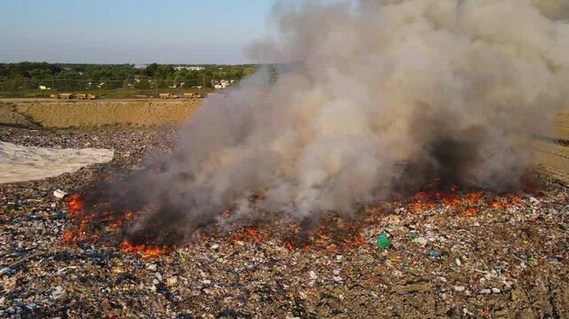 Trash fire burning at landfill with heavy smoke polluting environment