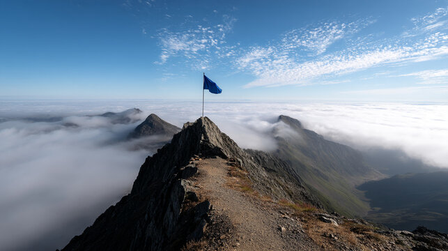 Blue flag atop mountain peak above cloudscape, representing achievement, success, and exploration of heights