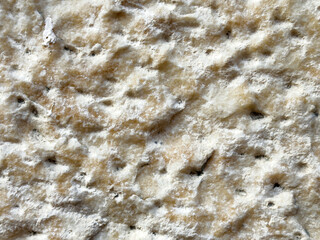 Close-up of textured rough stone surface with natural beige and white patterns