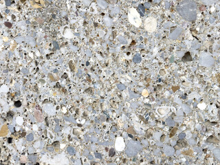 Close-up of textured gray speckled concrete surface with pebbles and aggregates