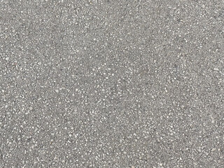 Close-up of rough textured gray asphalt surface with pebbles