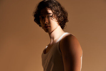 Stylish young man with curly hair poses confidently in a modern studio setting