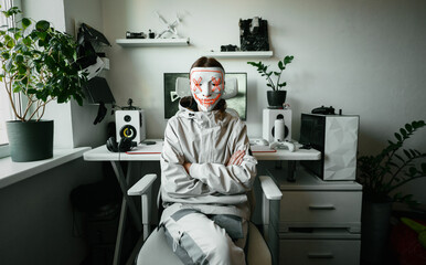 Person in white hacker mask sits confidently in modern home office, hiding face to represent anonymous identity, data privacy and digital safety. Concept of online security and personal protection