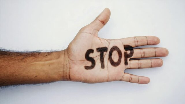 Hand shows "STOP" text. Perfect for warning messages, safety videos, attention-grabbing visuals. Palm with stop sign.