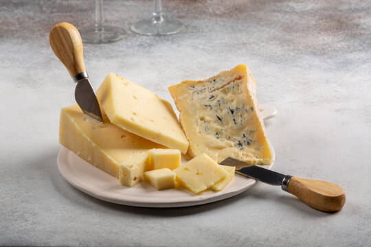 Cheese plate on concrete background. Italian cheeses - caciotta with fenugreek, blue cheese and asiago on ceramic board. Cheese platter.